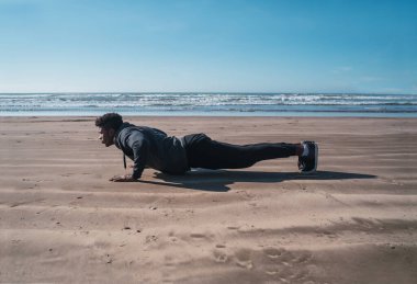 Sahilde şınav çeken atletik bir adamın portresi. Spor ve sağlıklı yaşam tarzı kavramı.