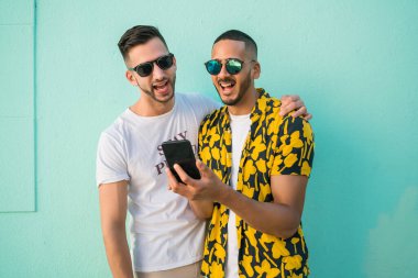 Cep telefonu kullanırken birlikte zaman geçiren mutlu eşcinsel çiftin portresi. Lgbt ve Aşk Konsepti.