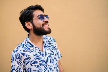 Genç yakışıklı adamın portresi yazdan zevk alıyor ve sarı arka planda yaz kıyafetleri giyiyor.. 