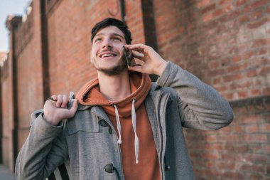 Sokakta telefonda konuşan yakışıklı bir gencin portresi. Şehir konsepti. İletişim konsepti.