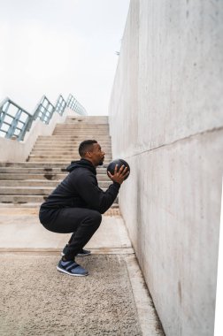 Dışarıda duvar topu egzersizi yapan atletik bir adamın portresi. Spor ve sağlıklı konsept.