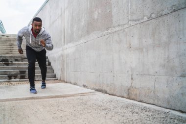 Gri arka planda koşan atletik bir adamın portresi. Spor ve sağlıklı yaşam tarzı.