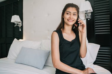Otel odasında telefonla konuşan genç bir iş kadınının portresi. İş seyahati kavramı.
