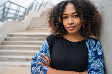Dışarıdaki beton merdivenlerde duran kıvırcık saçlı güzel Afro-Amerikan kadının portresi.. 