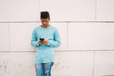 Sokakta cep telefonunu kullanan genç Asyalı adamın portresi. İletişim konsepti.