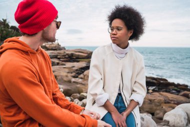 İki genç arkadaşın portresi, arka planda deniz otururken birlikte iyi vakit geçirip sohbet ediyorlar..