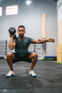 Spor salonunda dambılla egzersiz yapan genç sporcunun portresi. Crossfit, spor ve sağlıklı yaşam tarzı konsepti.