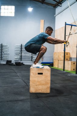 Atletik bir adamın kutu atlayışı egzersizi yaparken portresi. Crossfit, spor ve sağlıklı yaşam tarzı konsepti.