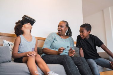 Evde VR gözlükleriyle oynayan Afrikalı Amerikalı büyükanne ve torunların portresi. Aile ve teknoloji kavramı.