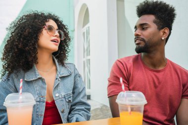 Kafeteryada taze meyve suyu içerken birlikte eğlenen ve eğlenen iki Afro arkadaşın portresi.
