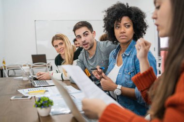 Genç yaratıcı tasarımcılar bir projede çalışıyor ve işyerindeki yeni düzen gelişimini tartışıyorlar. İş ve takım çalışması kavramı.