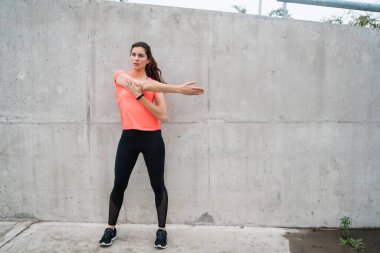 Açık havada egzersiz yapmadan önce kollarını açan atletik bir kadının portresi. Spor ve sağlıklı yaşam tarzı.