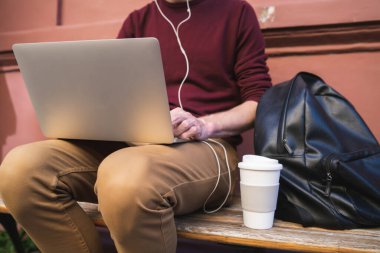Dışarıda otururken dizüstü bilgisayarını kullanan beyaz bir adamın portresi. Teknoloji konsepti.