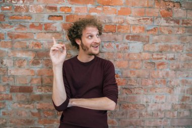 Sokaktaki tuğla duvara karşı bir fikri olan beyaz bir gencin portresi. Şehir konsepti.