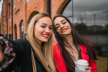 Sokakta selfie çeken iki genç arkadaşın portresi. Yaşam tarzı ve arkadaşlık kavramları.