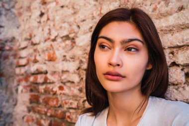 Duvara yaslanmış, sokakta genç Latin bir kadının yakın çekimi. Şehir konsepti.