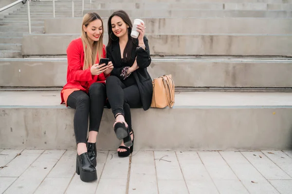 Retrato Dos Jóvenes Amigos Usando Teléfono Móvil Mientras Están Sentados —  Fotos de Stock