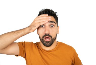 Şok olmuş yüz ifadesi olan ve beyaz arka planda kameraya şaşırmış genç bir adamın portresi..