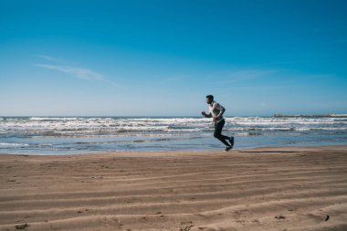 Sahilde koşan atletik bir adamın portresi. Spor, spor ve sağlıklı yaşam tarzı..