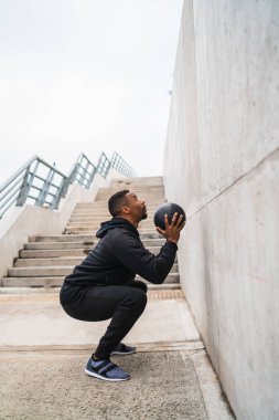 Dışarıda duvar topu egzersizi yapan atletik bir adamın portresi. Spor ve sağlıklı konsept.