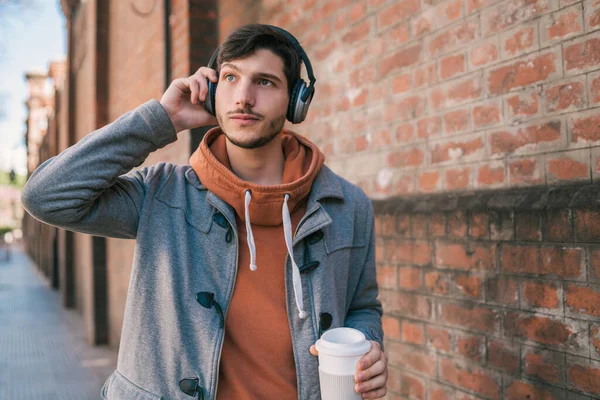 Portret Van Een Jongeman Met Oortjes Een Kop Koffie Tegen — Stockfoto