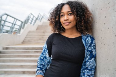 Dışarıdaki beton merdivenlerde duran kıvırcık saçlı güzel Afro-Amerikan kadının portresi.. 