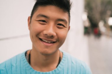 Genç Asyalı kendine güvenen ve sokakta günlük giysiler giyen bir adamın yakın çekimi..