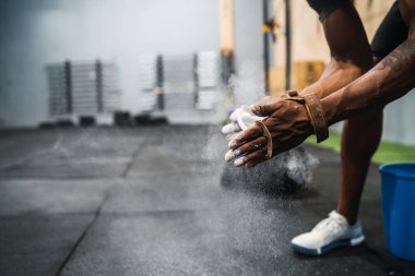 Zindelik portresi genç bir adamın tebeşir magnezyum tozuyla ellerini ovuşturması, spor salonunda antrenmana hazırlanması. Spor ve sağlıklı yaşam tarzı kavramı.