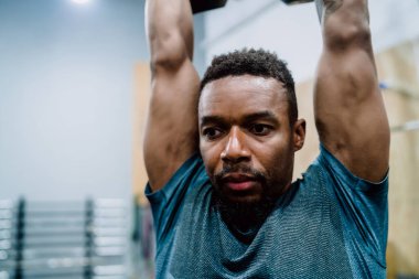 Spor salonunda çaydanlıkla egzersiz yapan genç bir sporcunun portresi. Crossfit, spor ve sağlıklı yaşam tarzı konsepti.