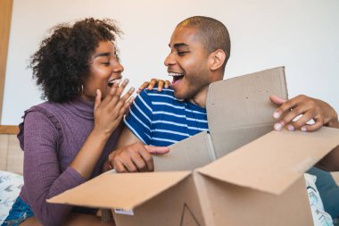 Mutlu genç Latin çiftin portresi evde bir paket açıyor. Teslimat, nakliye ve posta hizmeti konsepti. İnternetten al ve evde kal. Covid-19 Karantina.