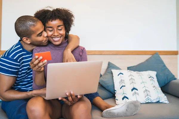 Portrait of happy young couple shopping online with credit card and laptop at home. Shop online. Buy food and products online. Prevention of COVID-19 infection.