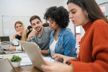 Genç yaratıcı tasarımcılar bir projede çalışıyor ve işyerindeki yeni düzen gelişimini tartışıyorlar. İş ve takım çalışması kavramı.