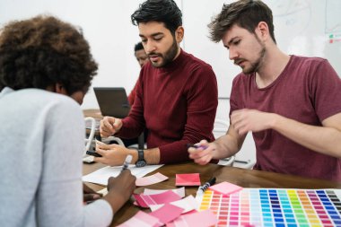 Genç yaratıcı tasarımcılar bir projede çalışıyor ve işyerindeki yeni düzen gelişimini tartışıyorlar. İş konsepti.