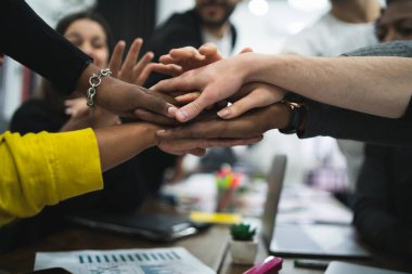 Yaratıcı tasarımcılardan oluşan bir ekip toplantı sırasında ellerini birleştiriyor. İş ve takım çalışması kavramı.