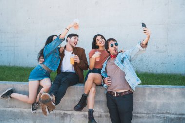 Birlikte eğlenen ve cep telefonuyla selfie çekerken eğlenen bir grup arkadaşın portresi. Yaşam tarzı ve arkadaşlık kavramı.