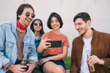 Birlikte eğlenen ve cep telefonuyla selfie çekerken eğlenen bir grup arkadaşın portresi. Yaşam tarzı ve arkadaşlık kavramı.