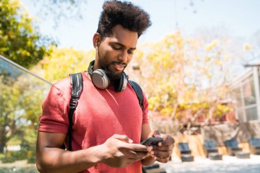 Dışarıda cep telefonunu kullanan genç afro adamın portresi. Teknoloji, kentsel ve yaşam tarzı kavramı.