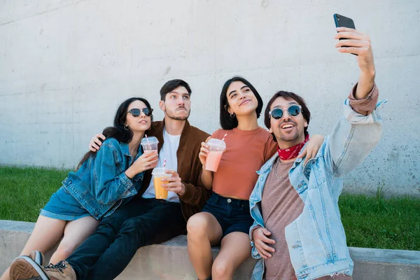 Birlikte eğlenen ve cep telefonuyla selfie çekerken eğlenen bir grup arkadaşın portresi. Yaşam tarzı ve arkadaşlık kavramı.