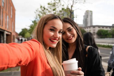 Sokakta selfie çeken iki genç arkadaşın portresi. Yaşam tarzı ve arkadaşlık kavramları.