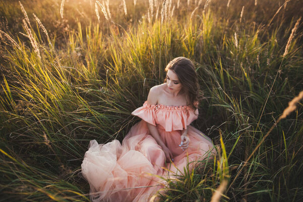 Young girl in peachy dress, in grass, alfresco in countryside