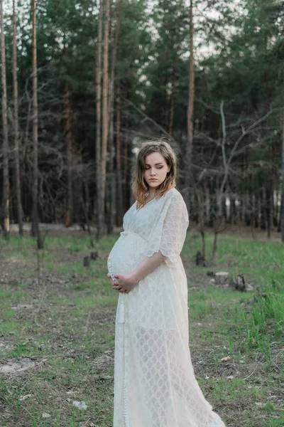 Kobieta w ciąży na trawniku w lesie — Zdjęcie stockowe