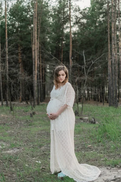 Kobieta w ciąży na trawniku w lesie — Zdjęcie stockowe