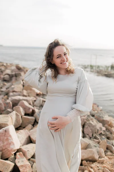 Zwangere vrouw op rotsachtige lakeshore — Stockfoto
