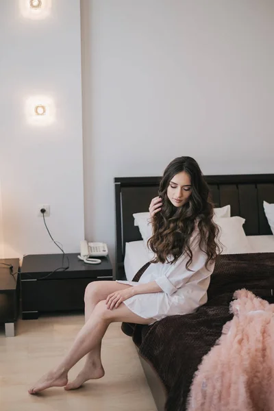 Kvinna sitter på sängen i sovrummet — Stockfoto