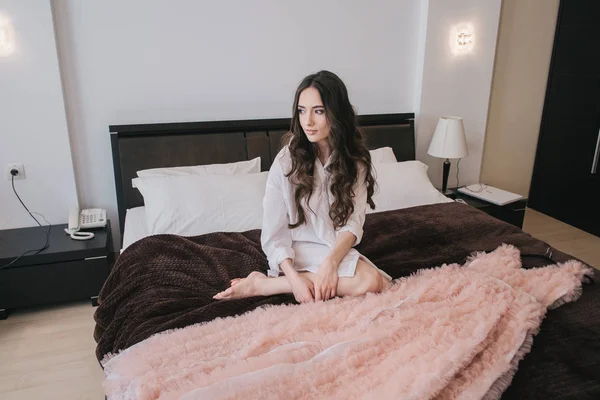 Flicka med persika klänning på säng — Stockfoto