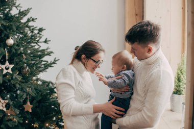 Genç çift Noel ağacı yakınındaki bir bebek tutan portresi