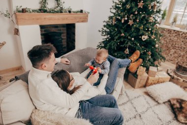 Genç çift kanepede erkek bebek tutan yükseltilmiş portresi 