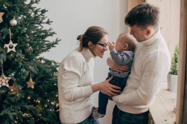 Genç çift Noel ağacı yakınındaki bir bebek tutan portresi