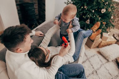 Genç çift kanepede erkek bebek tutan yükseltilmiş portresi 