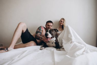 Köpek vasıl ev ile yatakta yatan genç dövmeli çift